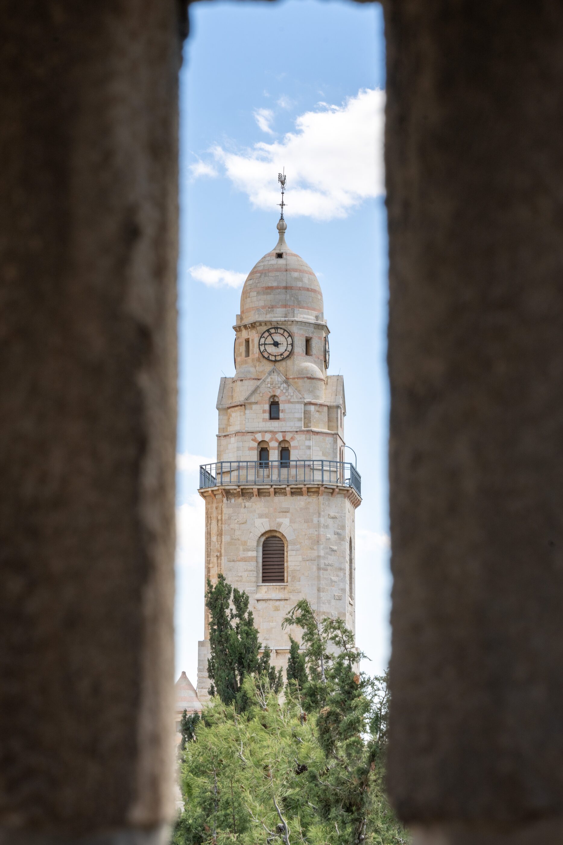 A church tower framed by a shadowed stone arch