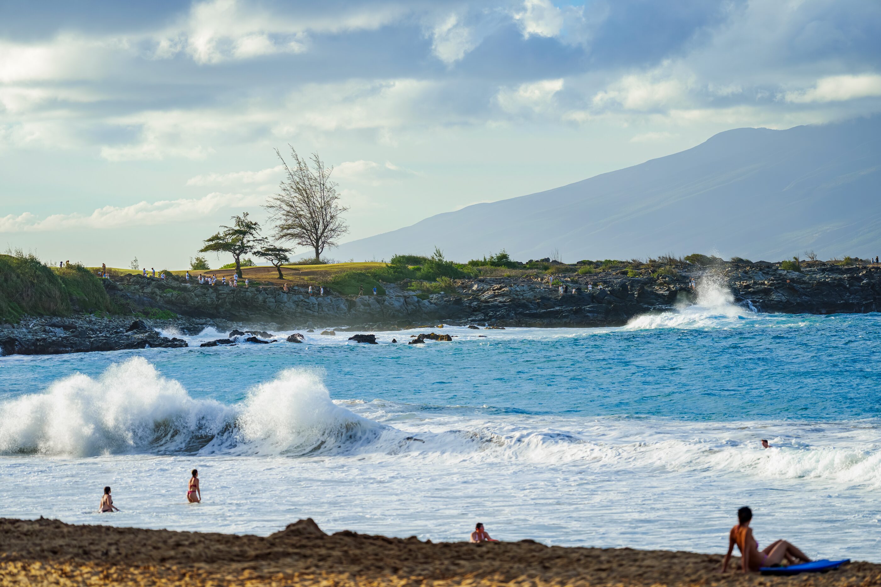 Surf rolling across a rocky tropical shoreline